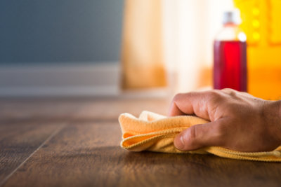male hand applying wood care products and cleaners on hardwood floor surface